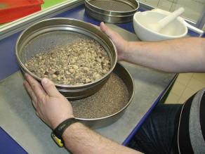 Mitarbeiter im Labor siebt eine Bodenprobe, um die Korngrößen zu trennen.