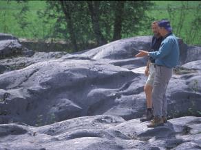 Zwei Personen diskutieren auf dem vom Gletscher abgeschliffenen Felshügel.