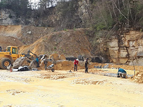 I Freiwillige Hellferinnen und Helfer unterstützen den Bau eines Laichgewässers, im Hintergrund ein Radlader im Steinbruch.