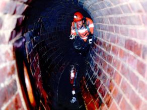 Ein Mann bei einer Inspektion in einem Abwasserkanal