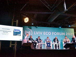 Podium des Öko-Forums mit sieben Referenten, die auf Stühlen sitzen