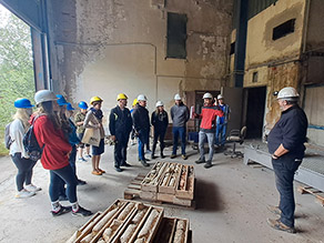 Teilnehmer vor Bohrkernkisten in einem einseitig offenen Raum der ehemaligen Glasfabrik