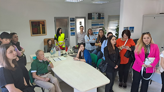 Teilnehmer des Evaluierungsworkshops in einem Büroraum der Kläranlage stehend, drei sitzen am Tisch, die dem Vortrag des Betriebsleiters zuhören