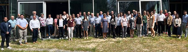 Etwa 40 Personen stehen im Freien für ein Gruppenbild zusammen, im Hintergrund die Fassade des Vortagssaals am LfU Augsburg.