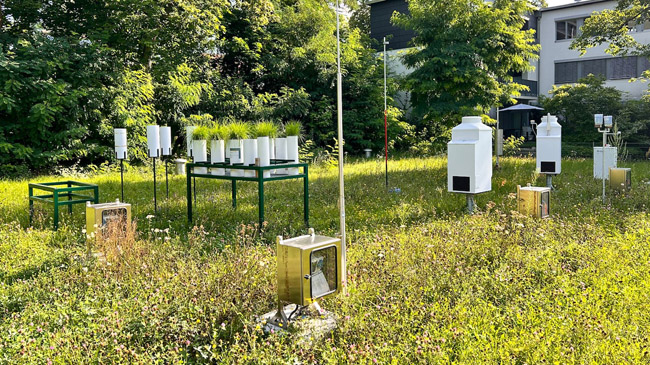 Die Abbildung zeigt eine Fotografie der Dauerbeobachtungsstation in Nürnberg im August 2024. Zu sehen sind unterschiedliche Sammelgeräte zur Sammlung von Luft- und Niederschlagsproben.