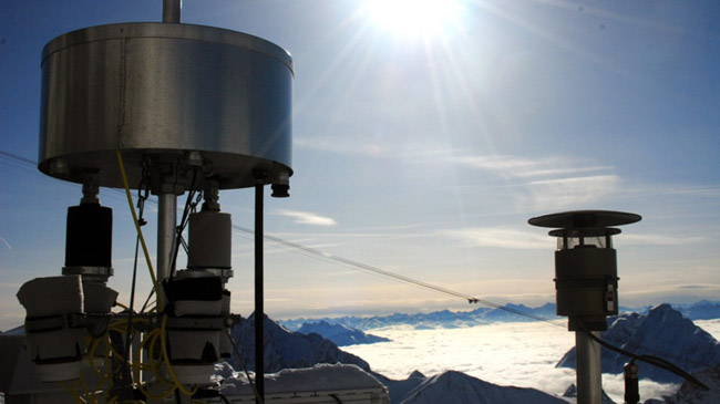 Aufnahme von zylindrischen Kartuschen, durch die Luft gesaugt wird, um Schadstoffe auf geeignetem Material anzureichern. Im Hintergrund die winterlichen Berge süd-östlich der Zugspitze unter blauem Himmel, während die Täler von einer Nebelschicht bedeckt sind. Aufnahme von zylindrischen Kartuschen, durch die Luft gesaugt wird, um Schadstoffe auf geeignetem Material anzureichern. Im Hintergrund die winterlichen Berge süd-östlich der Zugspitze unter blauem Himmel, während die Täler von einer Nebelschicht bedeckt sind.
