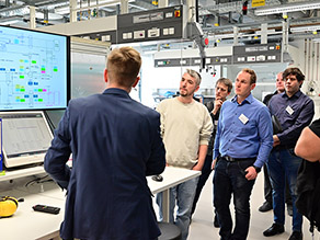 Teilnehmer einer Laborführung vor dem Steuerbildschirm einer Wärmepumpe