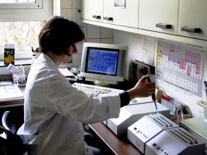 Laborantin, die eine Bakteriensuspension mittels einer Pipette in Probenröhrchen überführt.