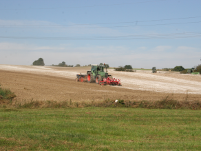 Traktor bei der Kalkung eines Ackers, die weiße Spuren auf der Oberfläche hinterlässt.