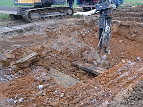 Ein Holzschwellenfundament wird mittels Bagger mit Scherenaufsatz ausgebaut.