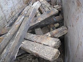 Ausgebaute Holzschwellenfundamente (sehen aus wie Eisenbahnschwellen) in einem Entsorgungscontainer.