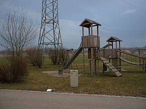 Ein großer Strommast steht neben einem Spielplatz