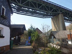 Brücke mit Stahlkonstruktion über Häusern und Gärten