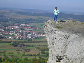 Eine Frau auf dem Gipfelfelsen des Staffelbergs blickt ins Tal.