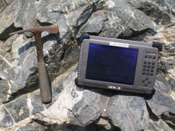 Geologenhammer und elektronisches Datenerfassungsgerät auf einem Felsen abgelegt