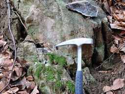 Verwitterte Felsen. Davor ist ein Hammer zum Größenvergleich aufgestellt