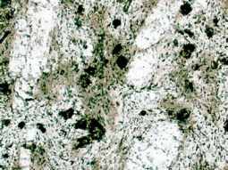 vergrößerte Detailansicht der Mineralzusammensetzung des Phonoliths. Vereinzelt große weiße Feldspat-Kristalle befinden sich in einer feinkörnigen Masse mit weißen und grünen Mineralen.