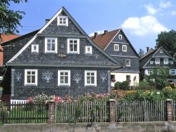 Mit schwarzem Schiefer und weißen Mustern in der Fassade verkleidetes Haus.