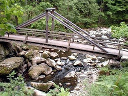 Steg über dem Flussbett mit großen Steinen