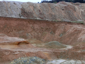 Geologische Schichten einer Bentonitgrube im Überblick von etwas weiter entfernt. Die unterste Schicht ist graublauer Bentonit.