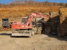 Bagger löst Gestein aus einem Quaderkalkbruch