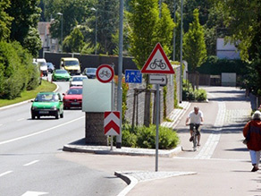 Beispiel einer städtischen Hauptverkehrsstraße. Eine Gabionenwand schützt die parallel verlaufende Spielstraße und ein angrenzendes Wohngebiet vor Verkehrslärm.