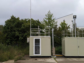 Außenansicht der Messtation links. Rechts ein Messcontainer des Lufthygienischen Landesüberwachungssystems Bayern zu sehen, der temporär für Vergleichsmessungen aufgebaut wurde.