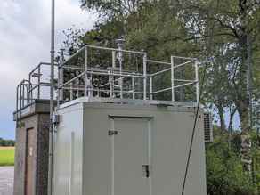 Im Vordergrund die Außenansicht der UFP-Messstation in München Johanneskirchen. Im Hintergrund die Messstation des Lufthygienischen Landesüberwachungssystems Bayern.