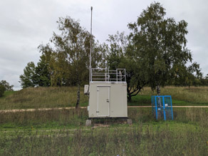 Außenansicht der UFP-Messstation in Regensburg auf dem Gelände der Universität. Auf der rechten Seite ein Gitterschrank, der temporär für Vergleichsmessungen aufgebaut wurde.