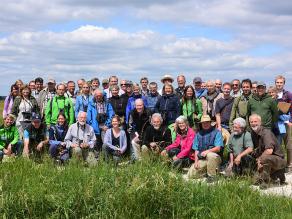 Auf dem Foto sind 53 Personen abgebildet. Sie haben sich für ein Gruppenfoto positioniert und blicken in Blickrichtung des Betrachters.