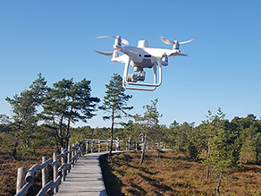 Eine weiße Drohne fliegt über einem Hochmoor.