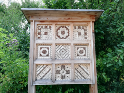 Wildbienenhotel aus Holz vor einer dichten Hecke. Wildbienenhotel aus Holz vor einer dichten Hecke.