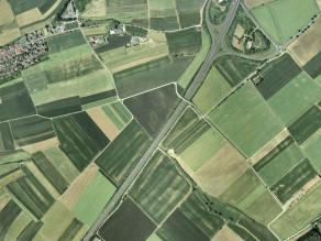 Luftbild mit Ackerlandschaft und vereinzelten Gehöften, durchschnitten von einer Autobahn und einer Autobahnanschlussstelle