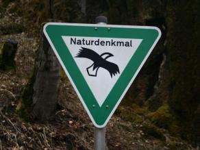 Dreieckiges Schild mit grünem Rand, dem Schriftzug Naturdenkmal und der Silhouette eines Seeadlers.