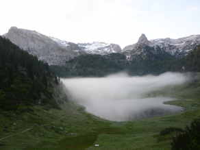 Berglandschaft mit einer deutlich sichtbaren, seeähnlichen Wolkendecke dicht am Boden zwischen den Bergen.