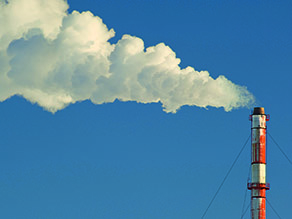 Kamin einer Industrieanlage mit deutlich sichtbarem Ausstoß einer Wolke.