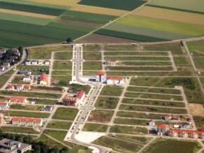 Luftaufnahme eines an Felder grenzenden Neubaugebiets am Ortsrand mit Straßen und noch bebaubaren Flächen
