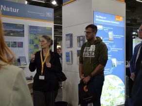 Das Foto zeigt eine Gesprächssituation mit der LfU-Präsidentin und Besuchern am Stand.