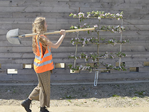 Kollegin mit Schaufel, vor dem Pavillon.
