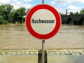Hinweisschild 'Hochwasser' vor einem überfluteten Bereich.