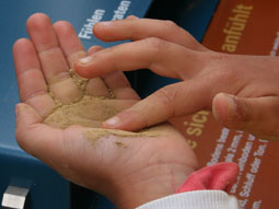 Ein Kind zerbröselt Sandstein in der Hand.