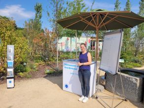 Stand der Aktion Grundwasserschutz auf der Landesgartenschau 2025 in Furth im Wald. Eine Mitarbeiterin steht vor den Ausstellungselementen im Freien. Stand der Aktion Grundwasserschutz auf der Landesgartenschau 2025 in Furth im Wald. Eine Mitarbeiterin steht vor den Ausstellungselementen im Freien.
