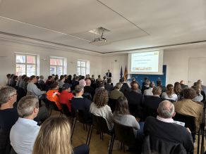 Grußworte des Regierungspräsidenten Rainer Haselbeck, Blick auf die Teilnehmenden von hinten. Grußworte des Regierungspräsidenten Rainer Haselbeck, Blick auf die Teilnehmenden von hinten.