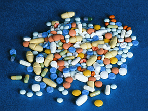 Viele bunte Tabletten liegen auf einer blauen Fläche