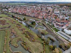 Luftaufnahme der Altmühl und des neuen, mäandrierenden Seitenarms. An das linkseitige Ufer grenzen Wiesen und Kleingewässer mit Schilfbeständen. Im Bereich des Seitenarms am stadtseitigen Ufer führen Wege entlang des Gewässers. Hinter der Hochwasserschutzanlage grenzt der Siedlungsbereich von Gunzenhausen an.
