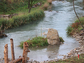 Eine kleine Grasinsel mit Felsen in einem Bach. Die Ufer sind geschwungen und grasbewachsen. Eine kleine Grasinsel mit Felsen in einem Bach. Die Ufer sind geschwungen und grasbewachsen.