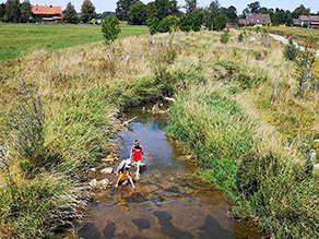 Zwei Kinder spielen im flachen Wasser eines renaturierten Bachs. Zwei Kinder spielen im flachen Wasser eines renaturierten Bachs.