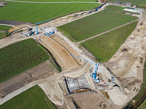 Luftaufnahme während der Baumaßnahme: Zwei neue Drosselbauwerke befinden sich im Bau. Neben den zwei Baugruben jeweils ein Turmdrehkran und Baumaterial. Luftaufnahme während der Baumaßnahme: Zwei neue Drosselbauwerke befinden sich im Bau. Neben den zwei Baugruben jeweils ein Turmdrehkran und Baumaterial.