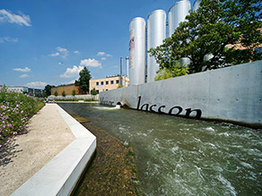 Ein kleiner Kanal wird durch eine niedrige Ufermauer, die zum Sitzen am Wasser einlädt, begrenzt. Daneben ein Gehweg und Blumenbeete. Eine Ufermauer auf der gegenüberliegenden Seite trägt den Schriftzug 'Wasser lassen'. Ein kleiner Kanal wird durch eine niedrige Ufermauer, die zum Sitzen am Wasser einlädt, begrenzt. Daneben ein Gehweg und Blumenbeete. Eine Ufermauer auf der gegenüberliegenden Seite trägt den Schriftzug 'Wasser lassen'.