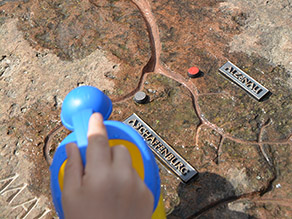Mit einer kleinen Gießkanne wird Wasser auf einen Felsen gegossen, in den das Gewässernetz der Kahl, des Mains und des Rheins gemeißelt sind. Die Städte Aschaffenburg, Alzenau, Frankfurt und Mainz sind dargestellt. Mit einer kleinen Gießkanne wird Wasser auf einen Felsen gegossen, in den das Gewässernetz der Kahl, des Mains und des Rheins gemeißelt sind. Die Städte Aschaffenburg, Alzenau, Frankfurt und Mainz sind dargestellt.